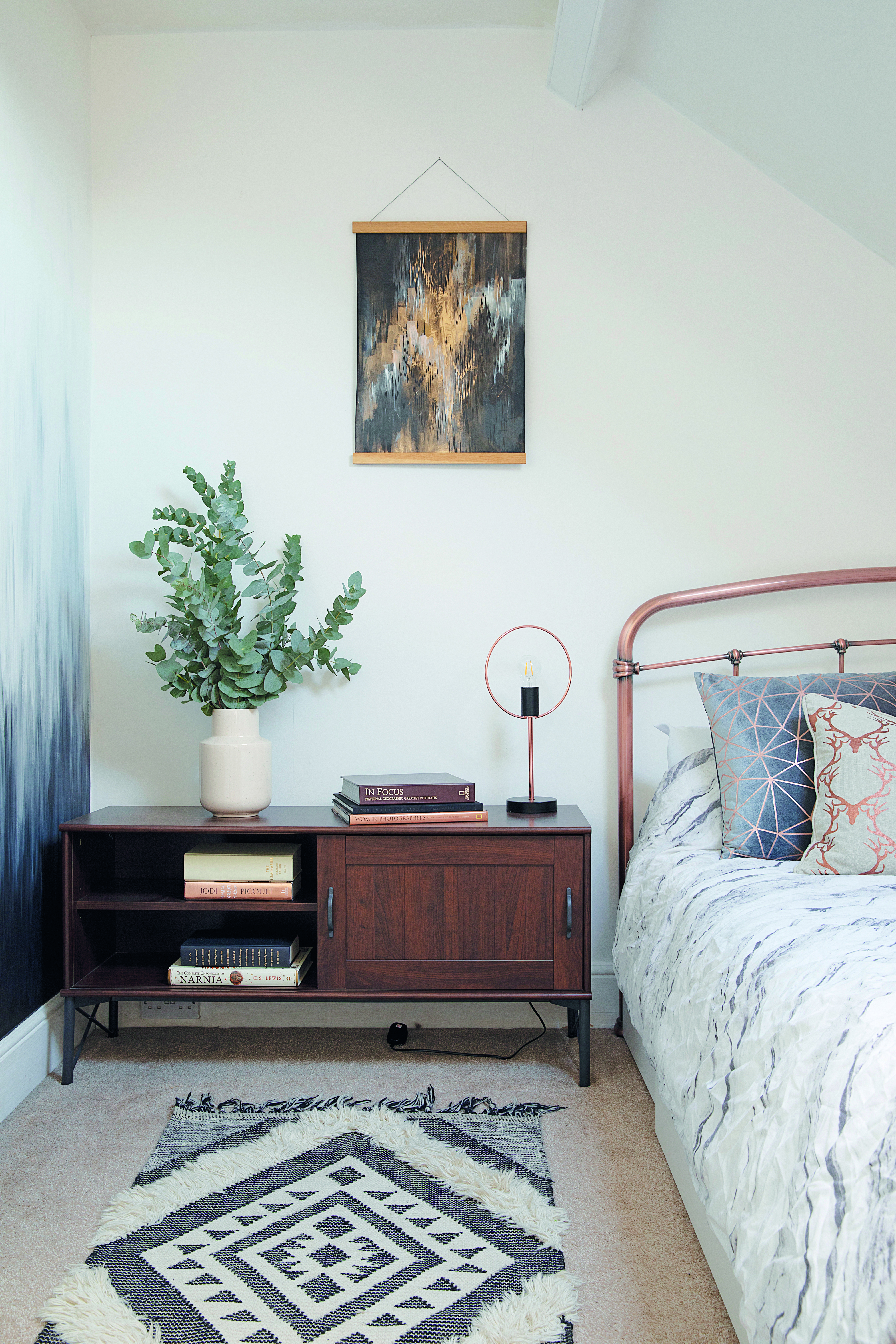 Charlotte has threaded copper elements throughout her scheme, like this bed frame from Next. The artwork is by Surfacephilia and the geometric cushions from Primark. The low unit is from IKEA A guest bedroom with a copper bed from Next