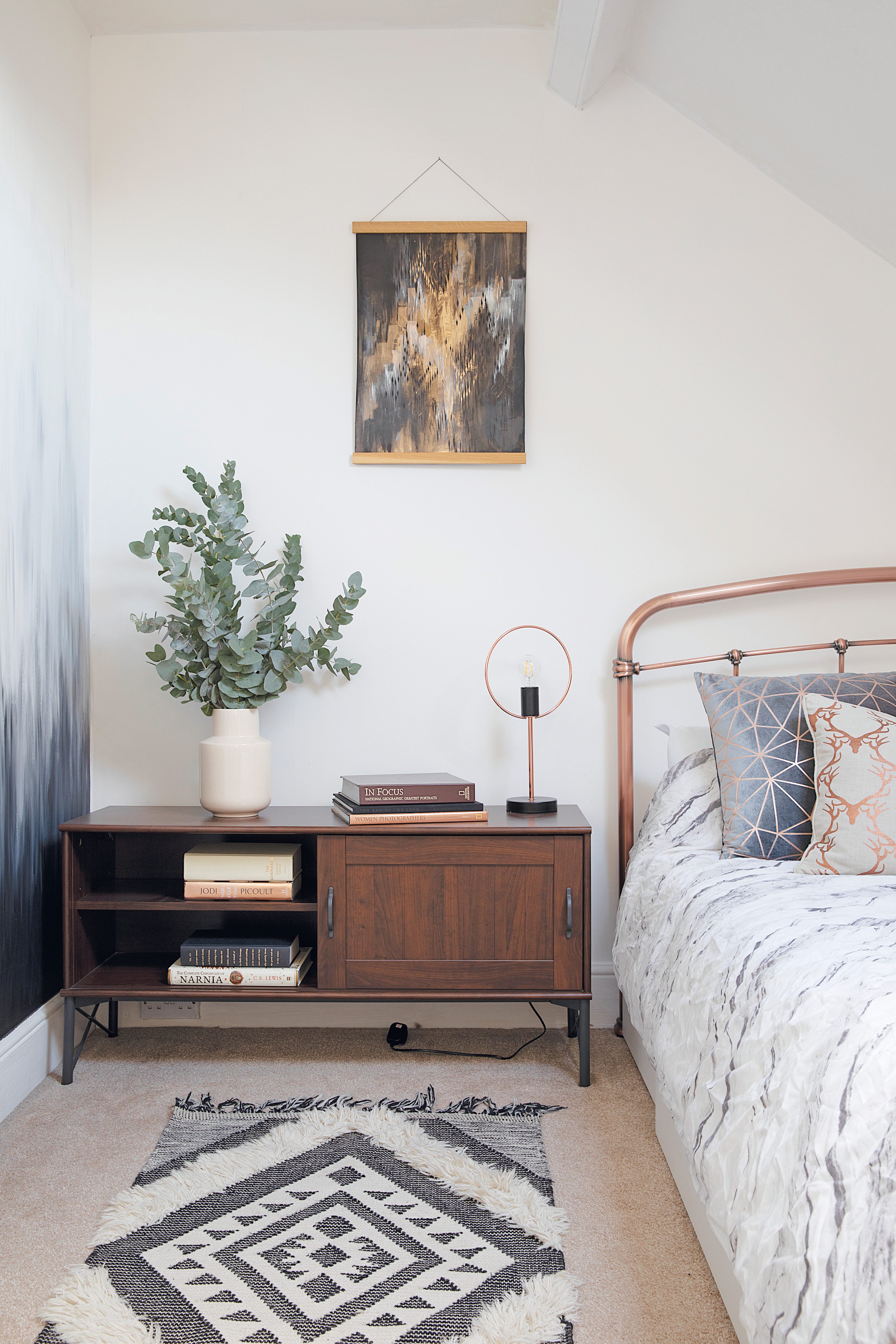 Charlotte has threaded copper elements throughout her scheme, like this bed frame from Next. The artwork is by Surfacephilia and the geometric cushions from Primark. The low unit is from IKEA A guest bedroom with a copper bed from Next