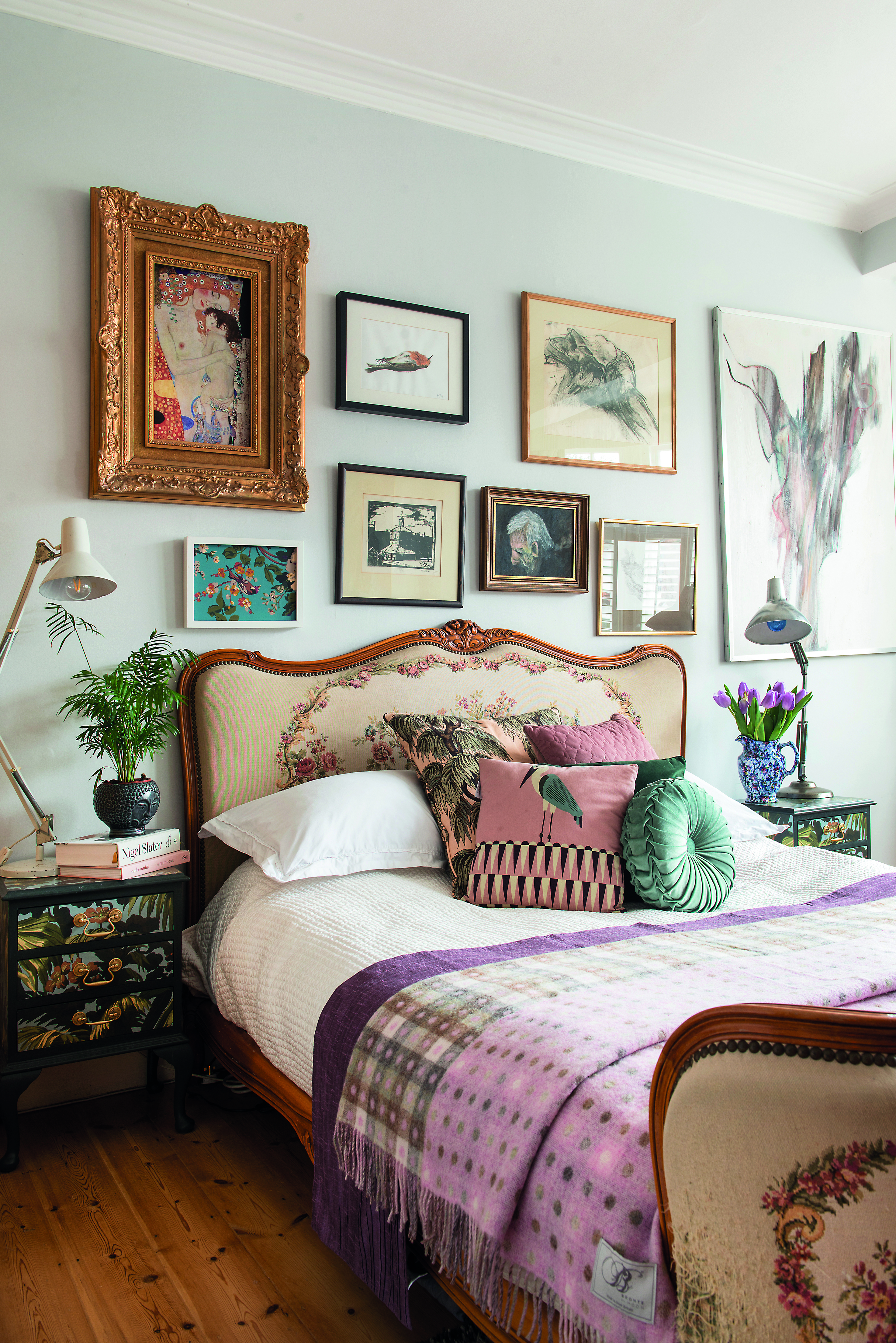 The bedroom walls are painted in Farrow & Ball’s Blackened, which acts as a subtle backdrop for the eclectic gallery wall. Vintage reading lamps add a contrasting functional feel beside the decorative upholstered bed