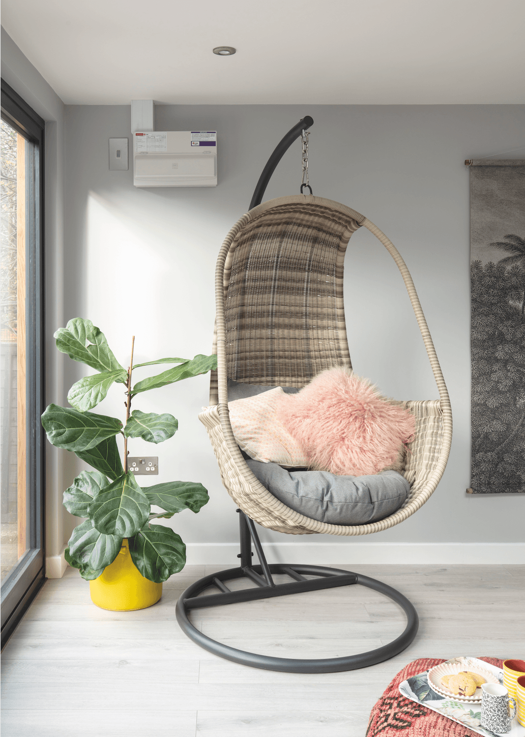 A funky wicker hanging chair gives the room wow-factor and a sheepskin cushion in pink brings in some pastel colour. The jungle wall chart adds further interest Garden room makeover: 'Vintage touches give our modern garden room character'