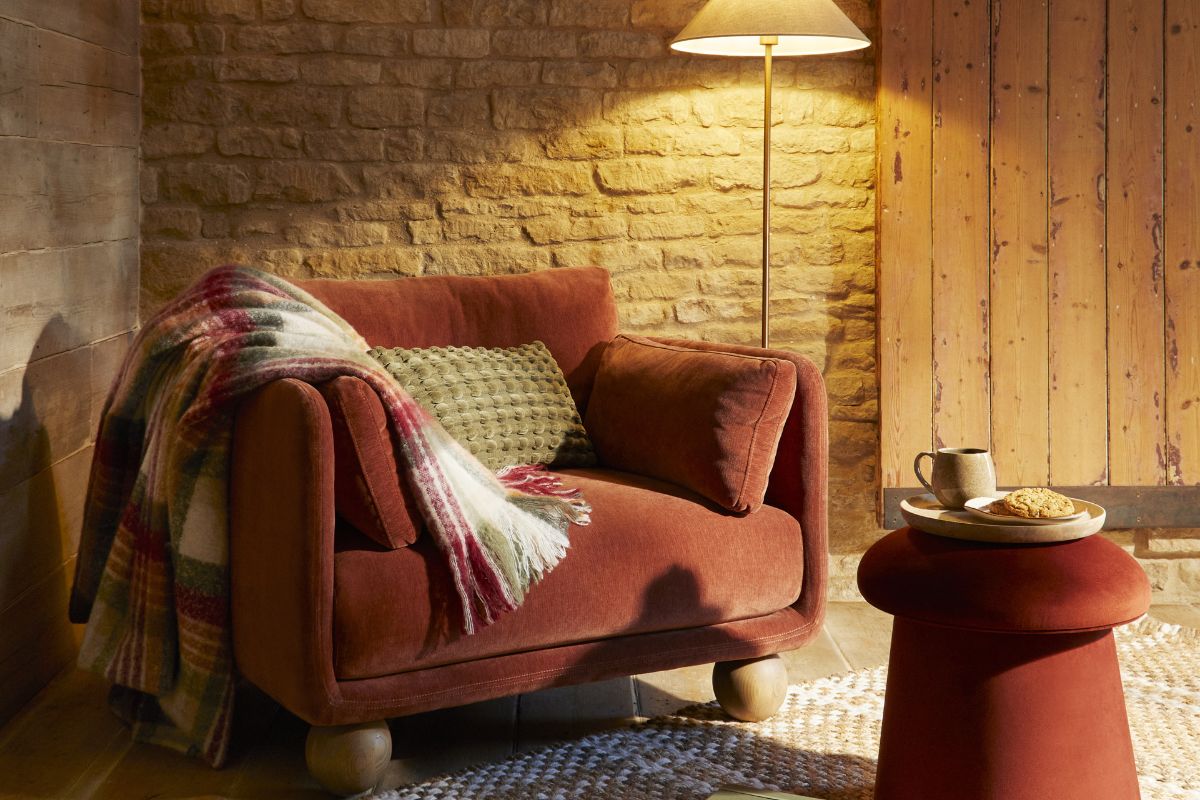 Sofa with throw and well lit by lamp and pouffe with coffee on it