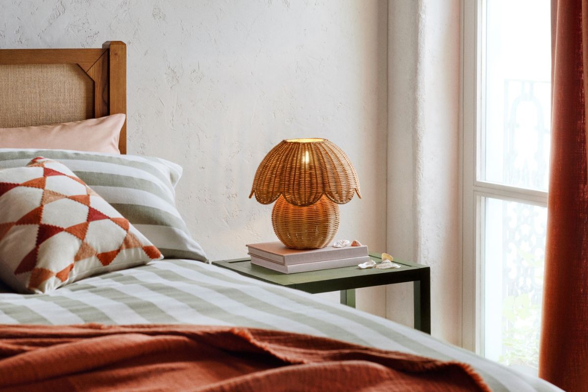 Bed made up with rattan lamp on bedside table