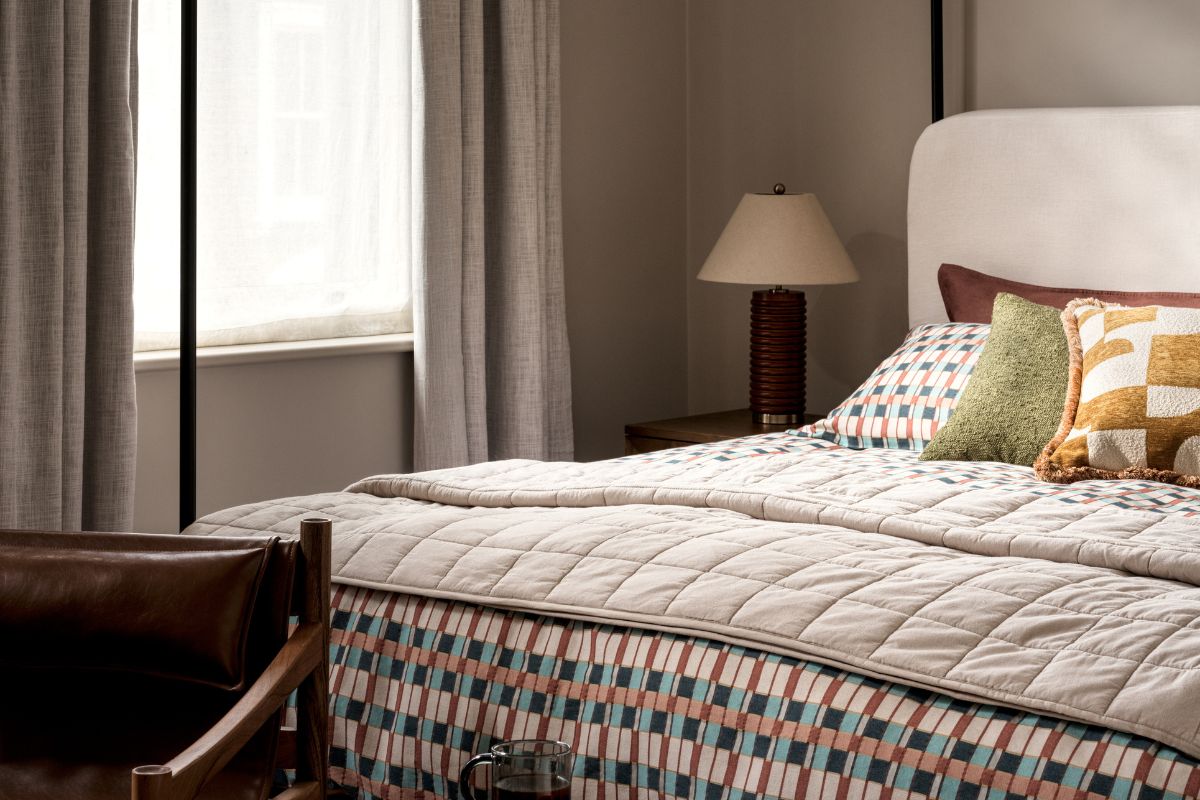 Bed with bedside table with lamp on it and bright cushions