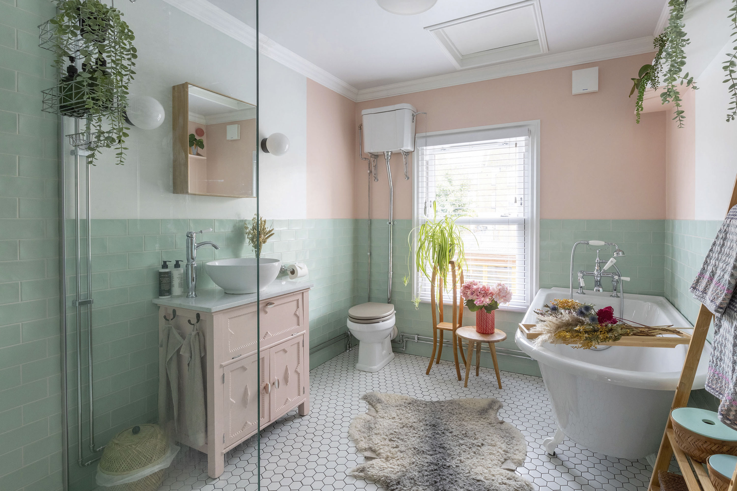 'Renovating gave us a blank canvas for our colourful, creative home' A traditional toilet and bath sit beautifully alongside modern pink and off-white walls, Victoria Plum Annecy Green matt wall tiles and Tiles Direct white and pink Hex floor tiles