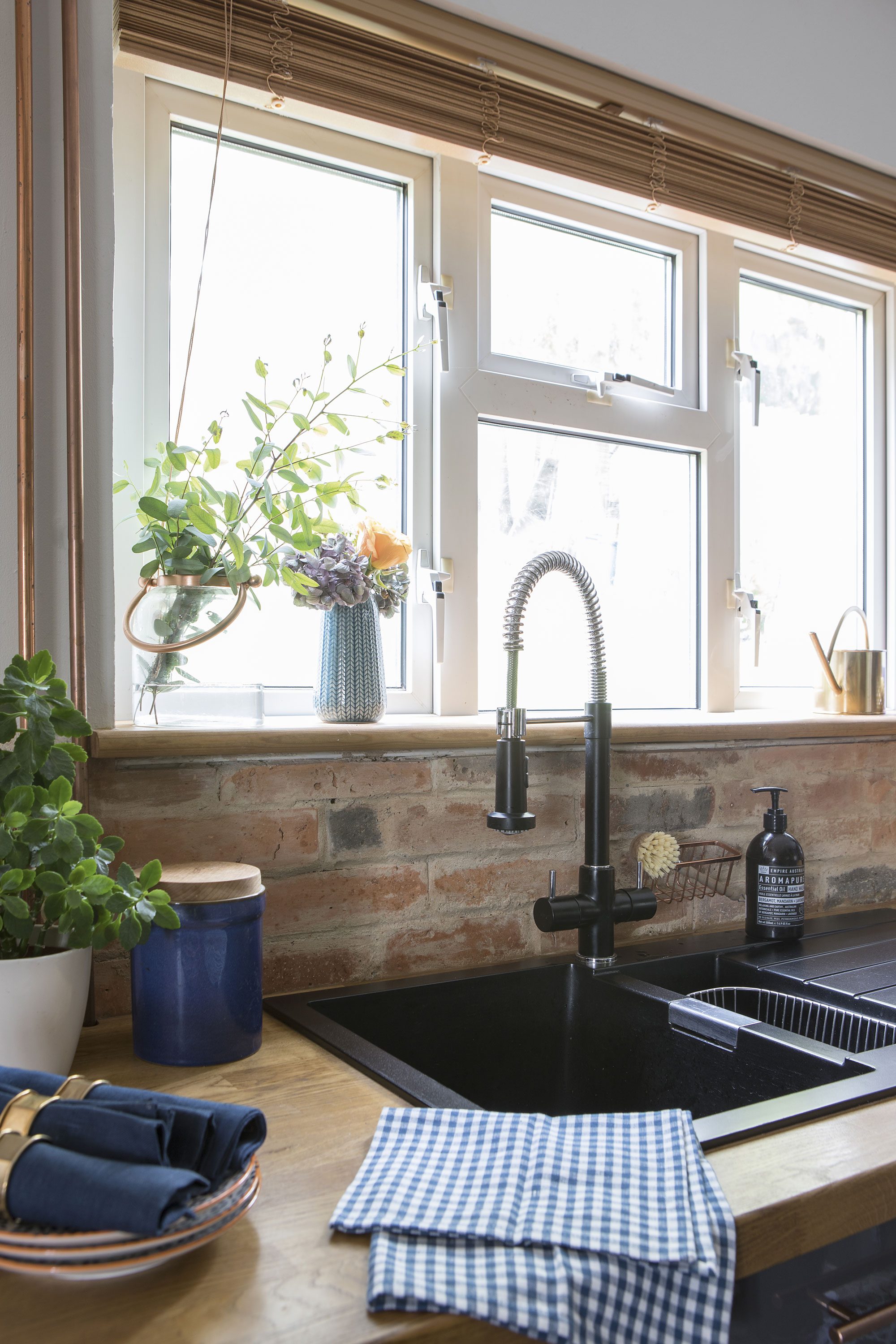An easy-to-maintain black composite sink with a chunky hose tap is a functional choice for an industrial aesthetic. Dace moved the sink in front of the window to overlook the garden, a concept new to her that she’s grown to like since moving to the UK An easy-to-maintain black composite sink with a chunky hose tap is a functional choice for an industrial aesthetic. Dace moved the sink in front of the window to overlook the garden, a concept new to her that she’s grown to like since moving to the UK