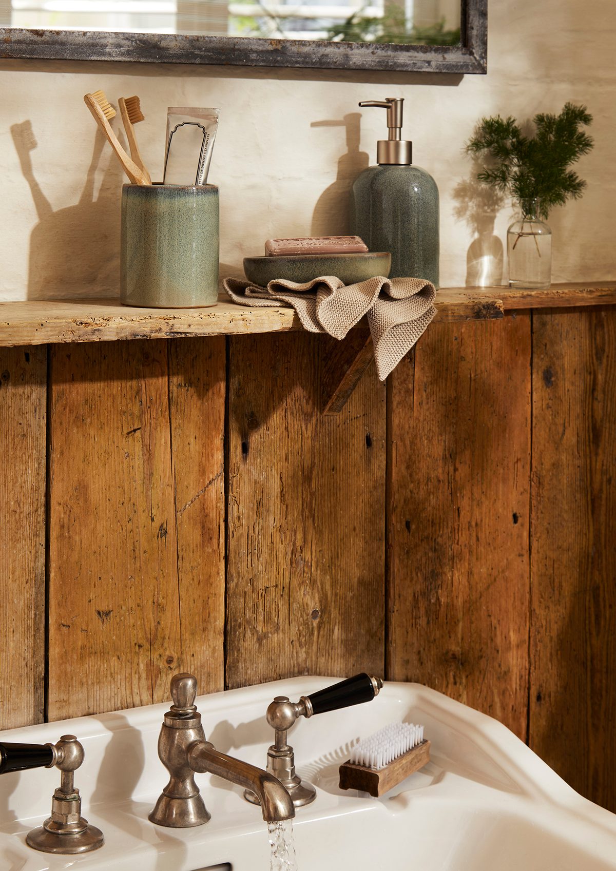 A ceramic soap dispenser, dish and toothbrush holder on a sink