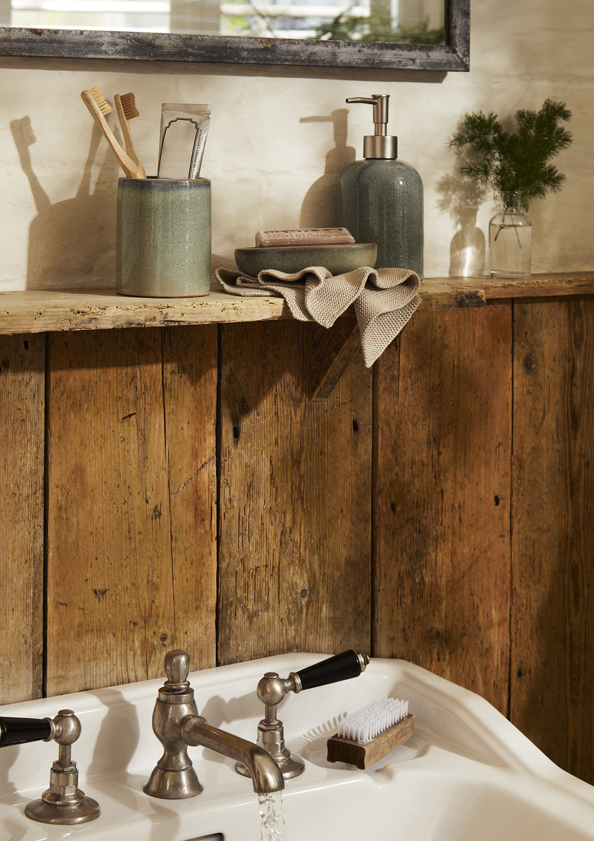 A ceramic soap dispenser, dish and toothbrush holder on a sink