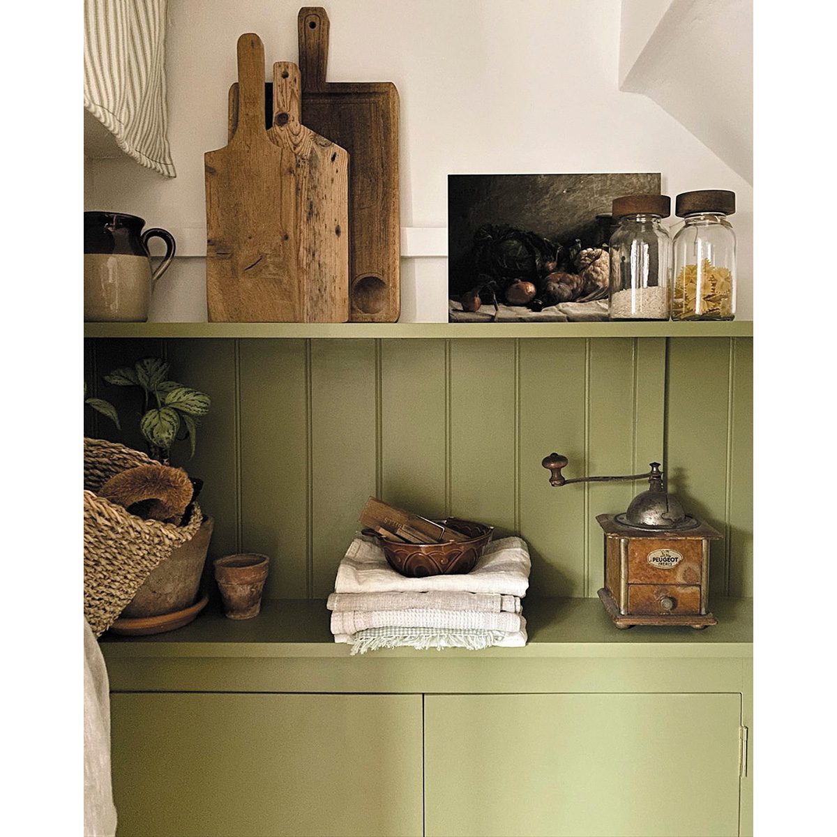 A shelf and cupboard painted in an olive green shade