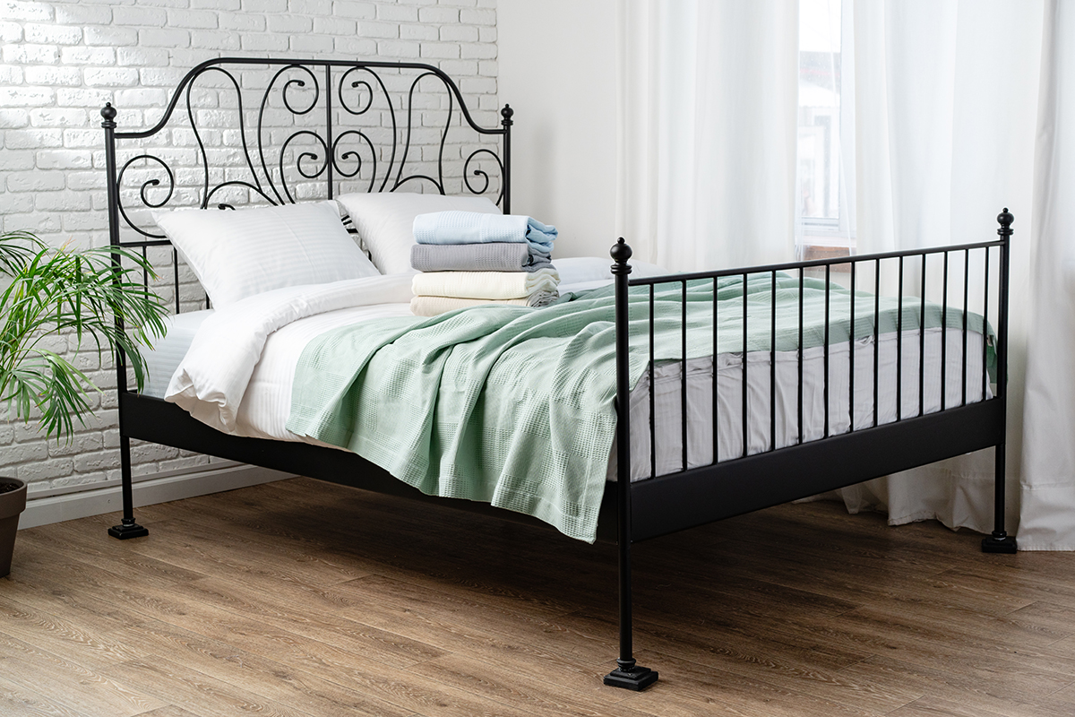 A bed with a black metal frame against a white wall