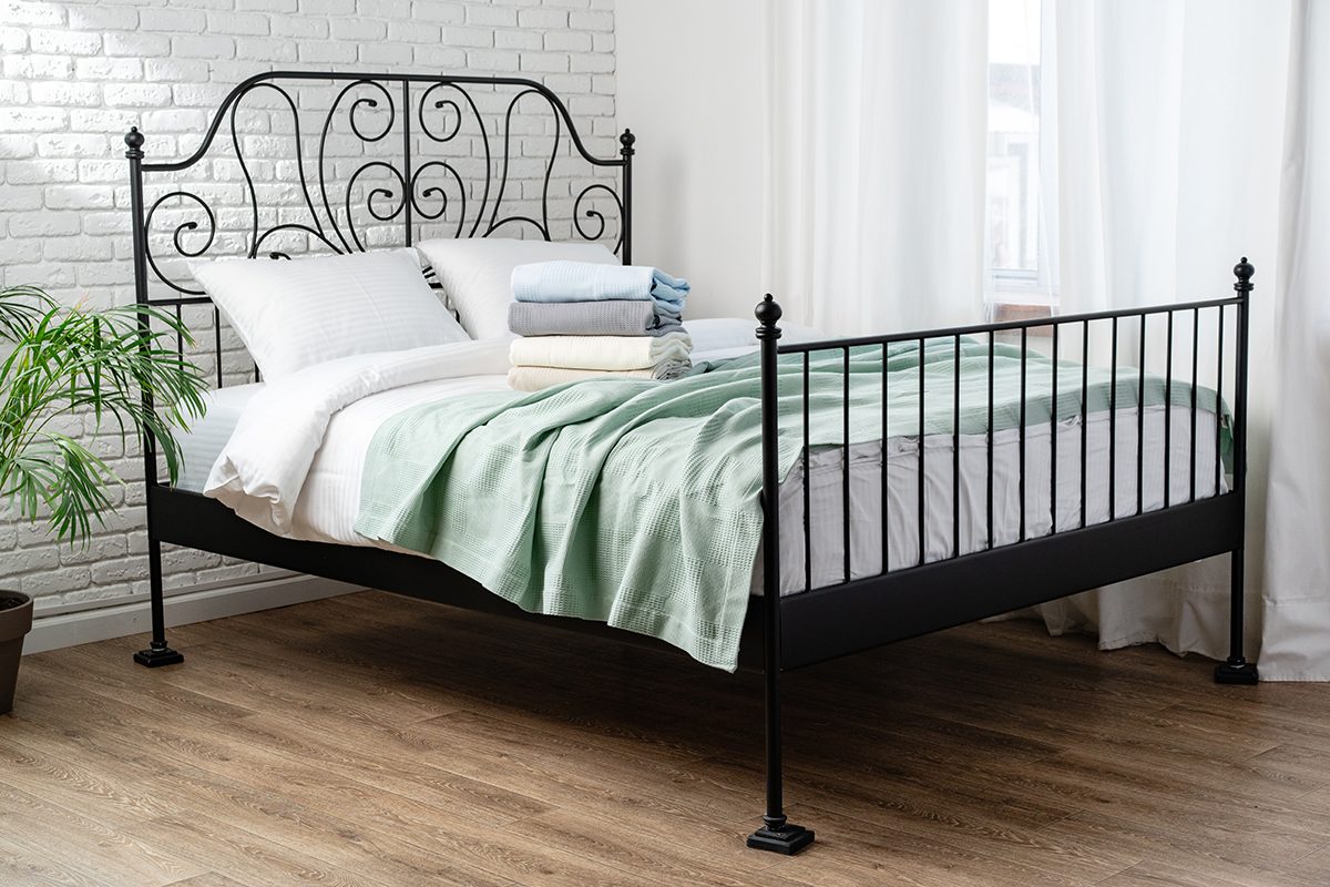 A bed with a black metal frame against a white wall