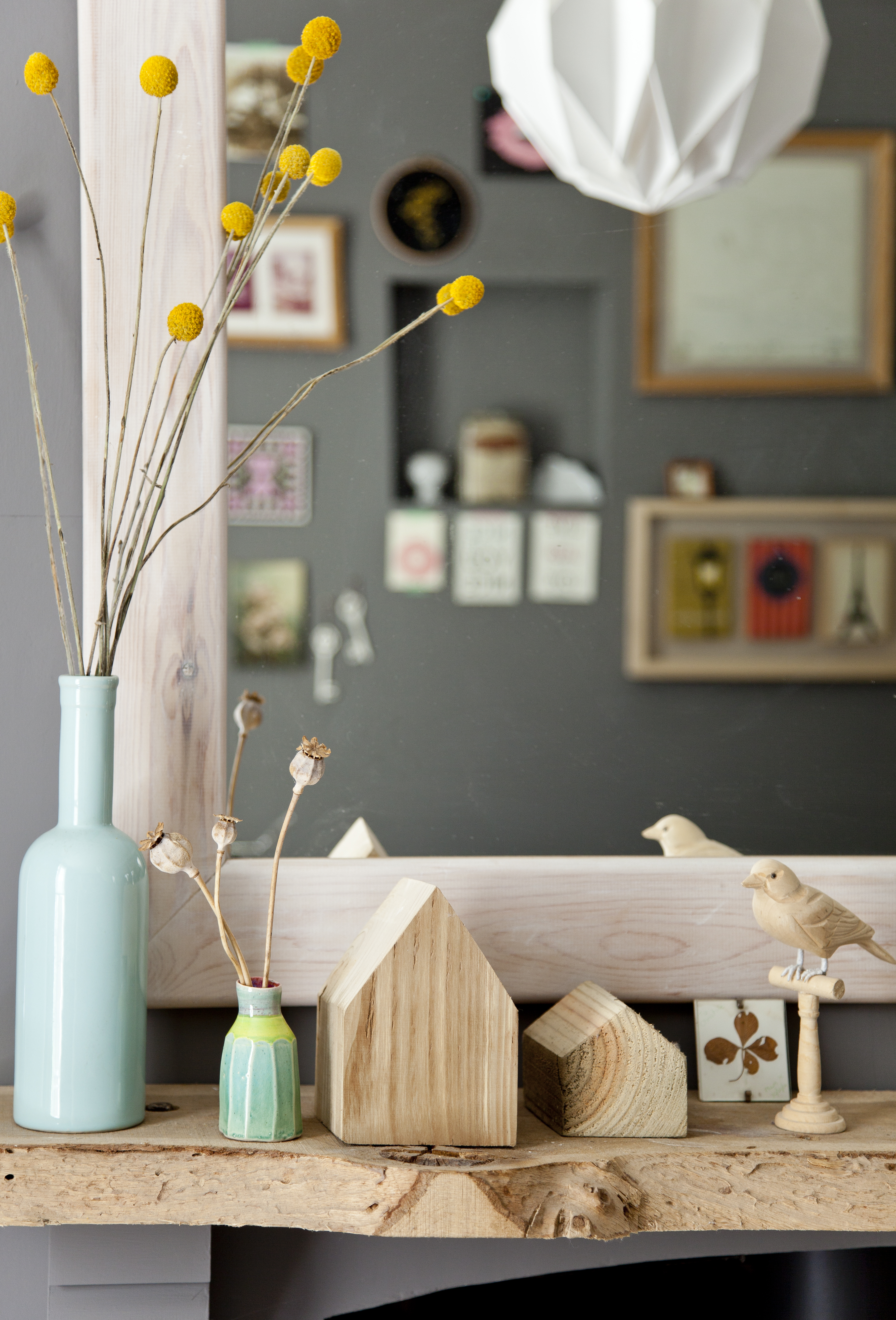 Natural wooden ornaments, vases and cheerful, dried yellow plants give a minimalist Scandi look Natural wooden ornaments and a blue vase full of dried yellow flowers