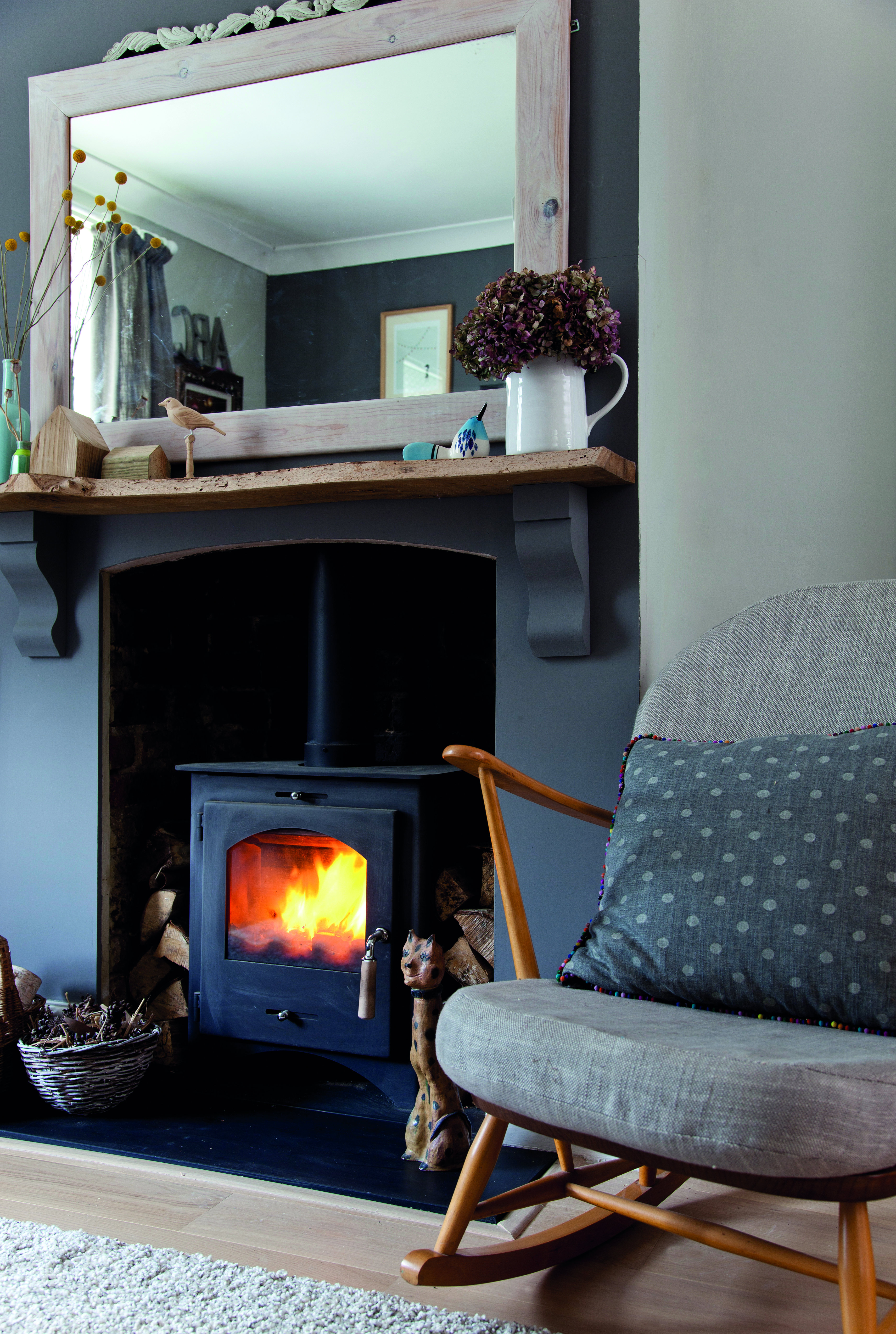 The Ercol rocker was one of Christine’s eBay bargains. Newly reupholstered, it looks very cosy next to her fireplace A grey Ercol rocking chair next to a log burner