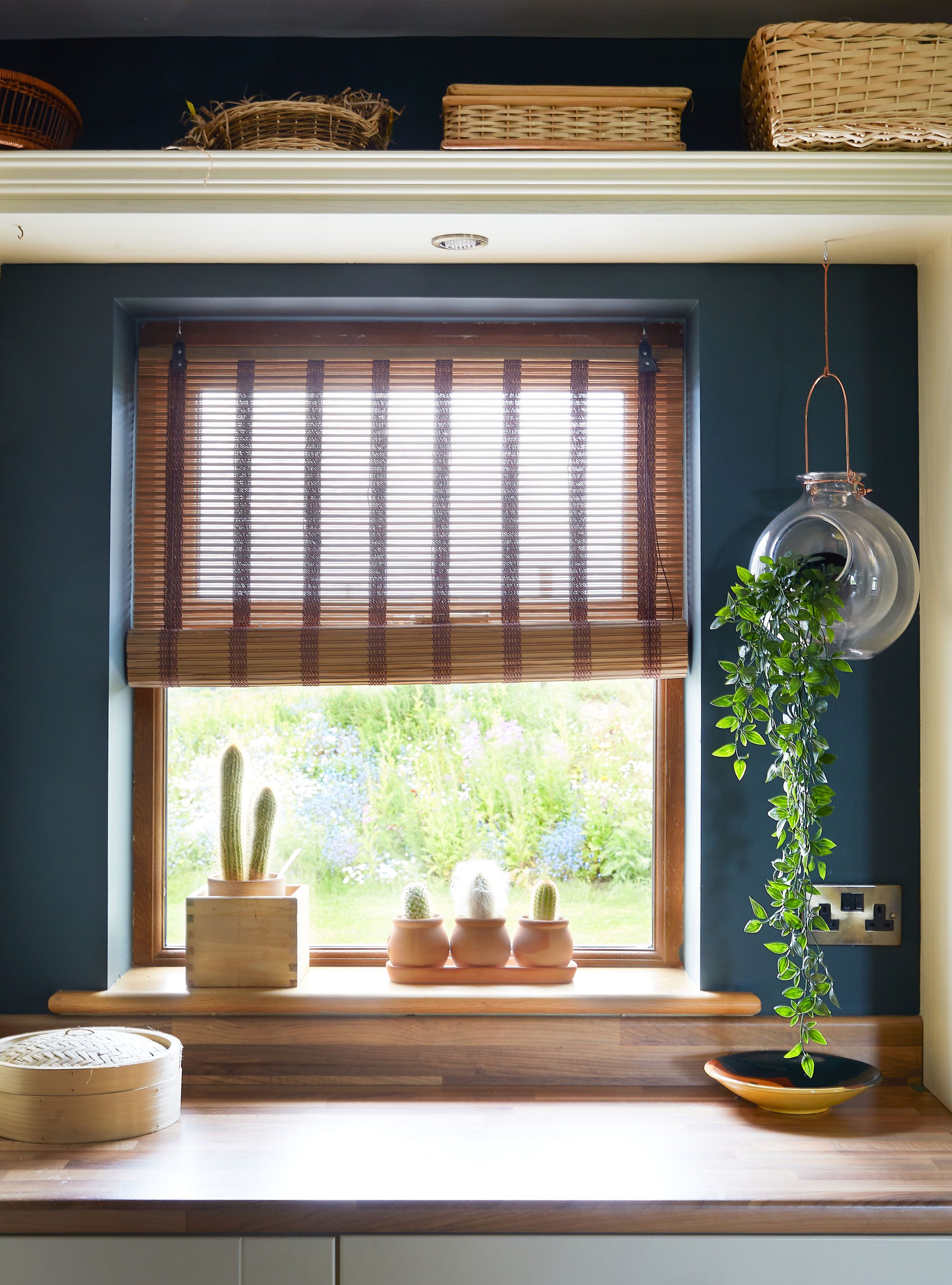 The natural textures of woven baskets, bamboo, timber and terracotta sing out against the deep teal of the kitchen walls