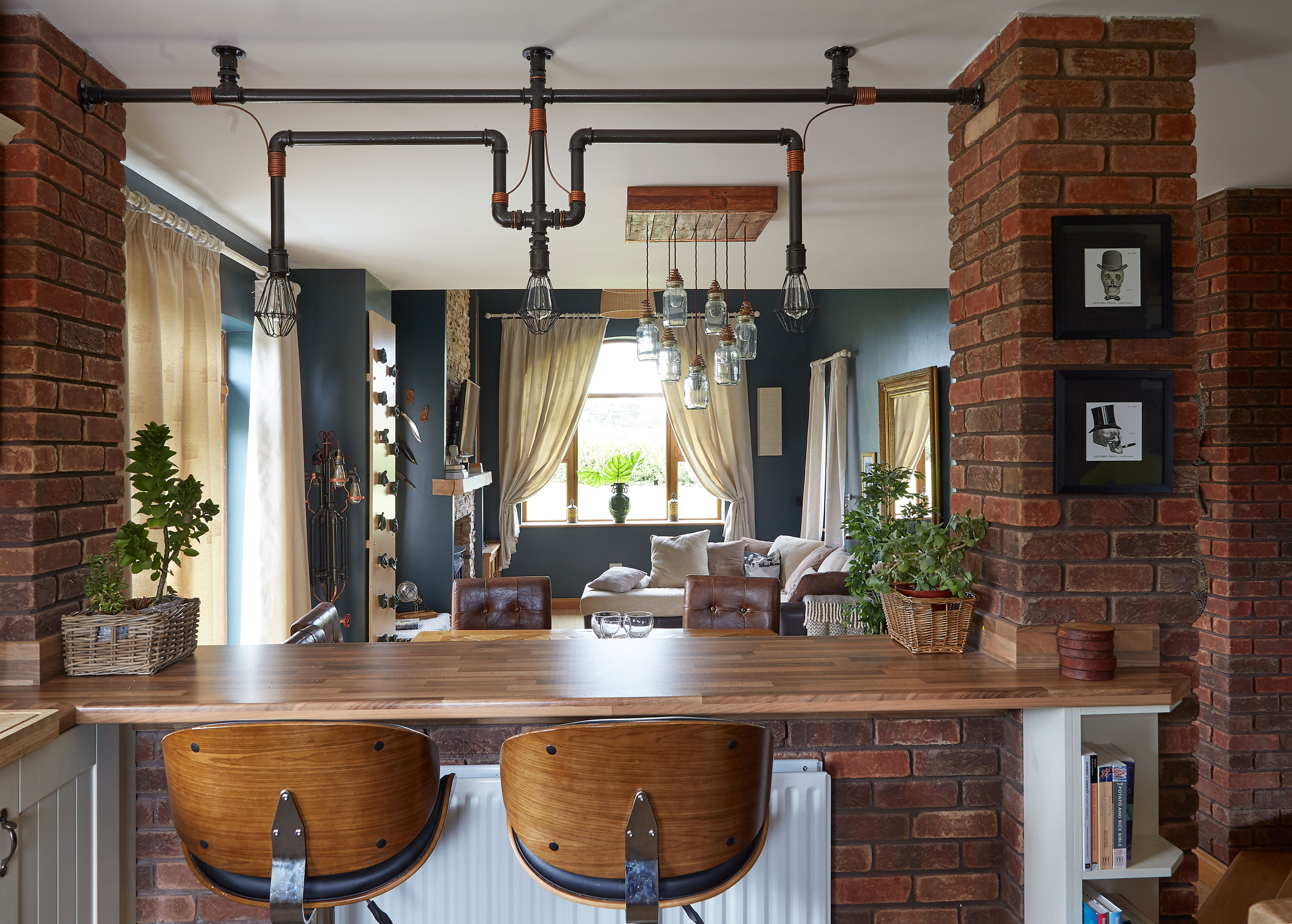 The breakfast bar overlooks the dining and living rooms, and serves as a divider to break up the open-plan space between them and the kitchen. Above it hangs one of the distinctive light fittings Shane has designed and built using plumbing parts The breakfast bar overlooks the dining and living rooms, and serves as a divider to break up the open-plan space between them and the kitchen. Above it hangs one of the distinctive light fittings Shane has designed and built using plumbing parts