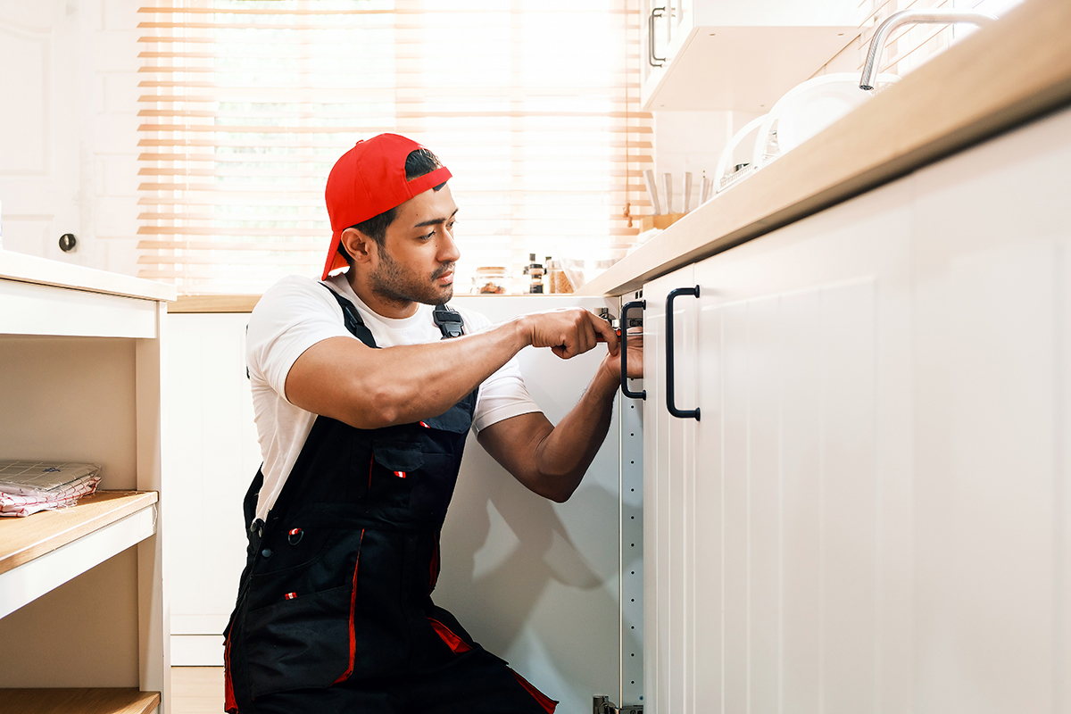 A man installing a kitchen cabinet handle