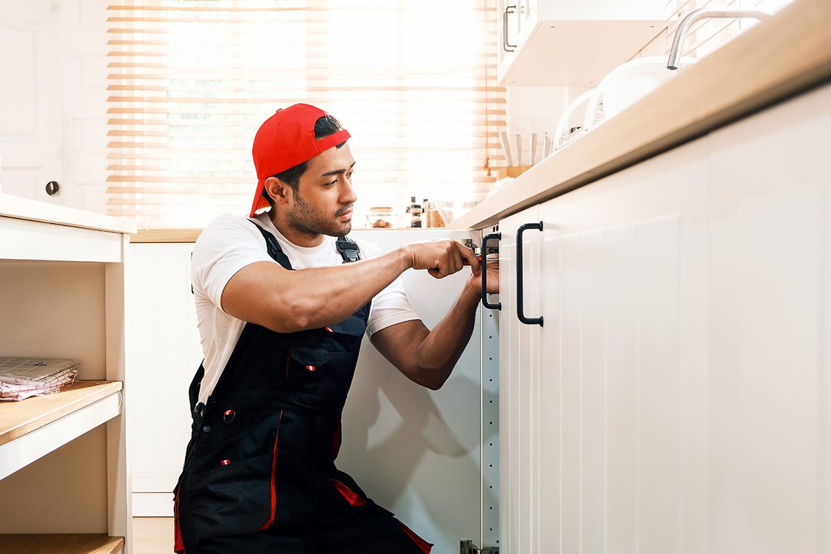 A man installing a kitchen cabinet handle