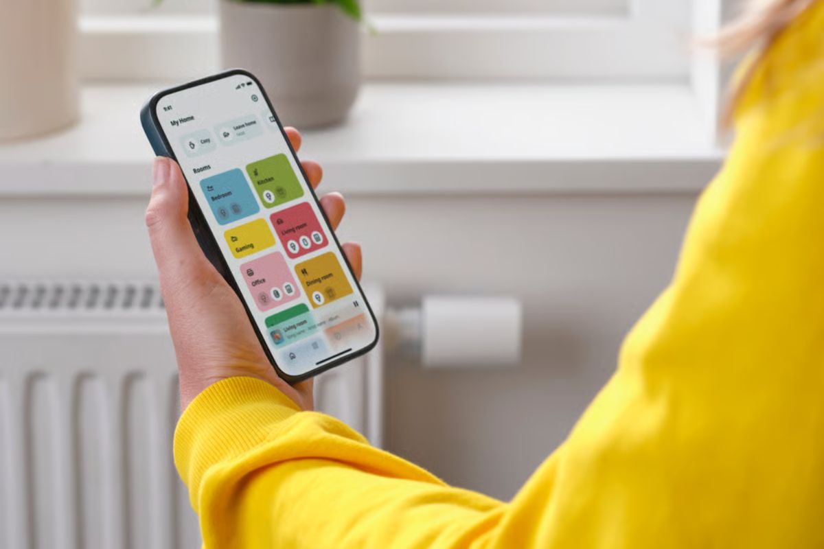 Person holds phone which has smart tech on it with radiator in background