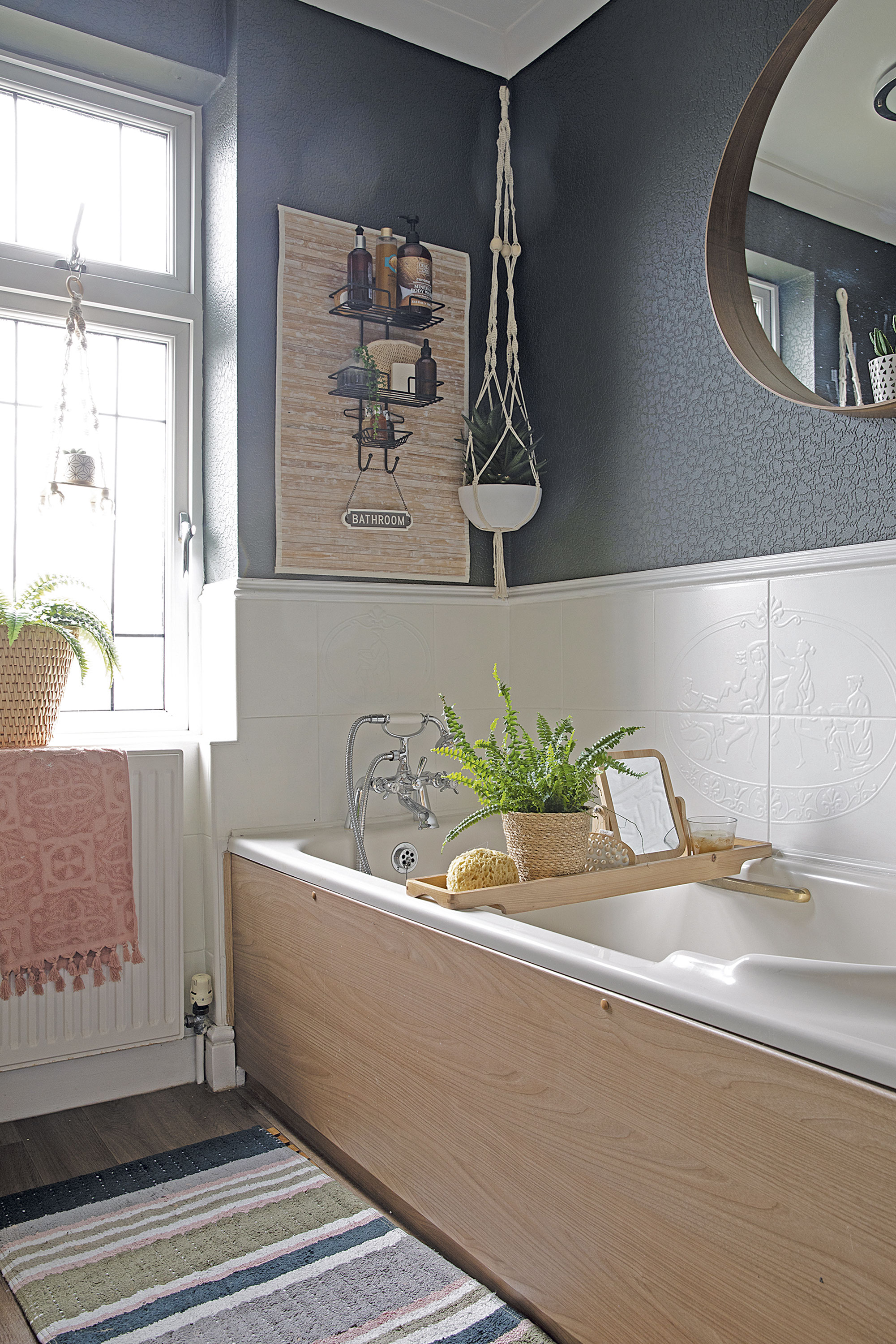 The old bathroom suite has been dressed up with an IKEA mirror, George Home bathmat and bath bridge. ‘To make a feature on the wall I created some storage using a spare bathmat and shower caddy,’ says Leanne The old bathroom suite has been dressed up with an IKEA mirror, George Home bathmat and bath bridge. ‘To make a feature on the wall I created some storage using a spare bathmat and shower caddy,’ says Leanne