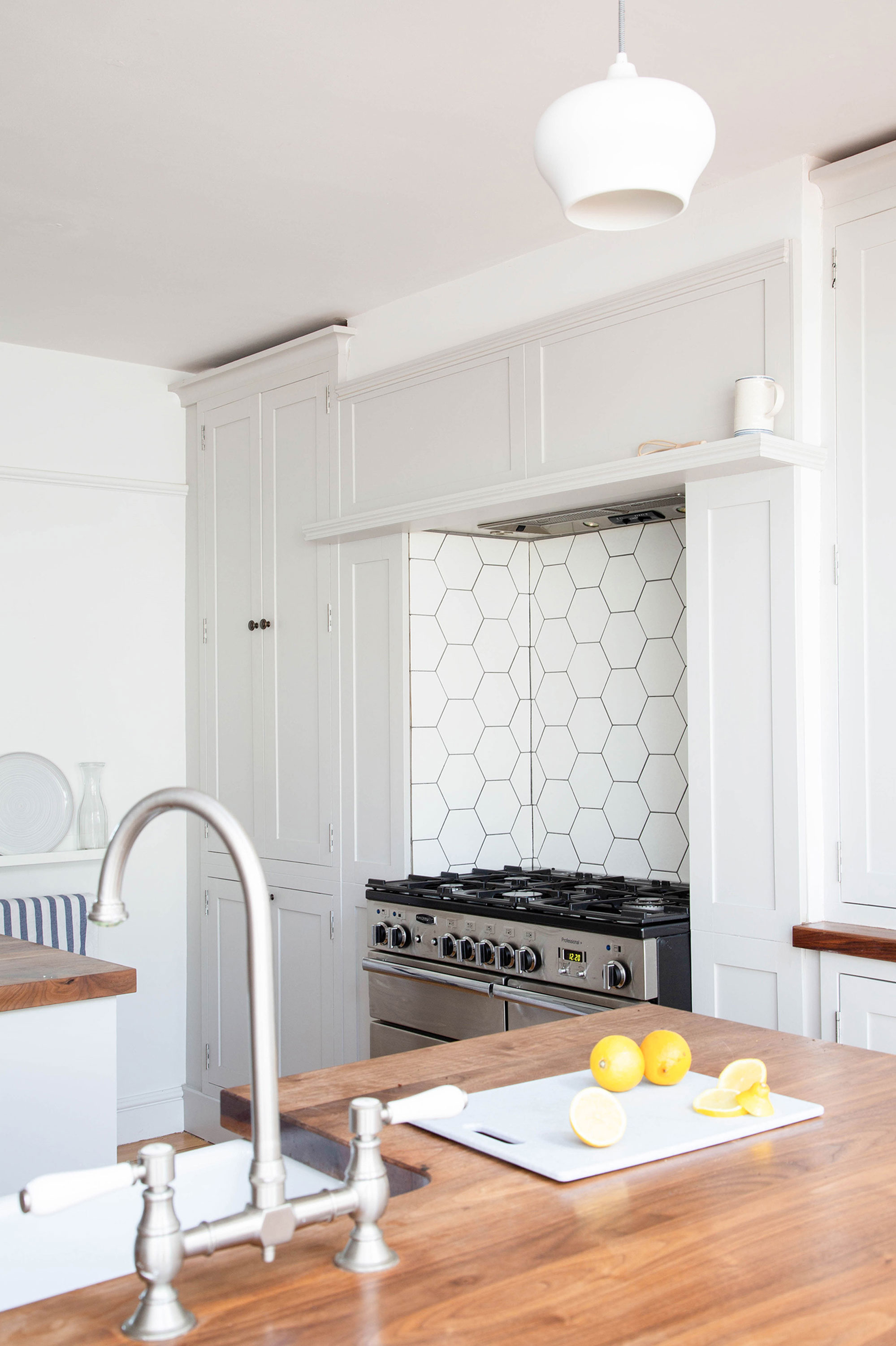 The couple paired simple Shaker-style cabinets with wooden worktops and a modern hexagonal tile splashback