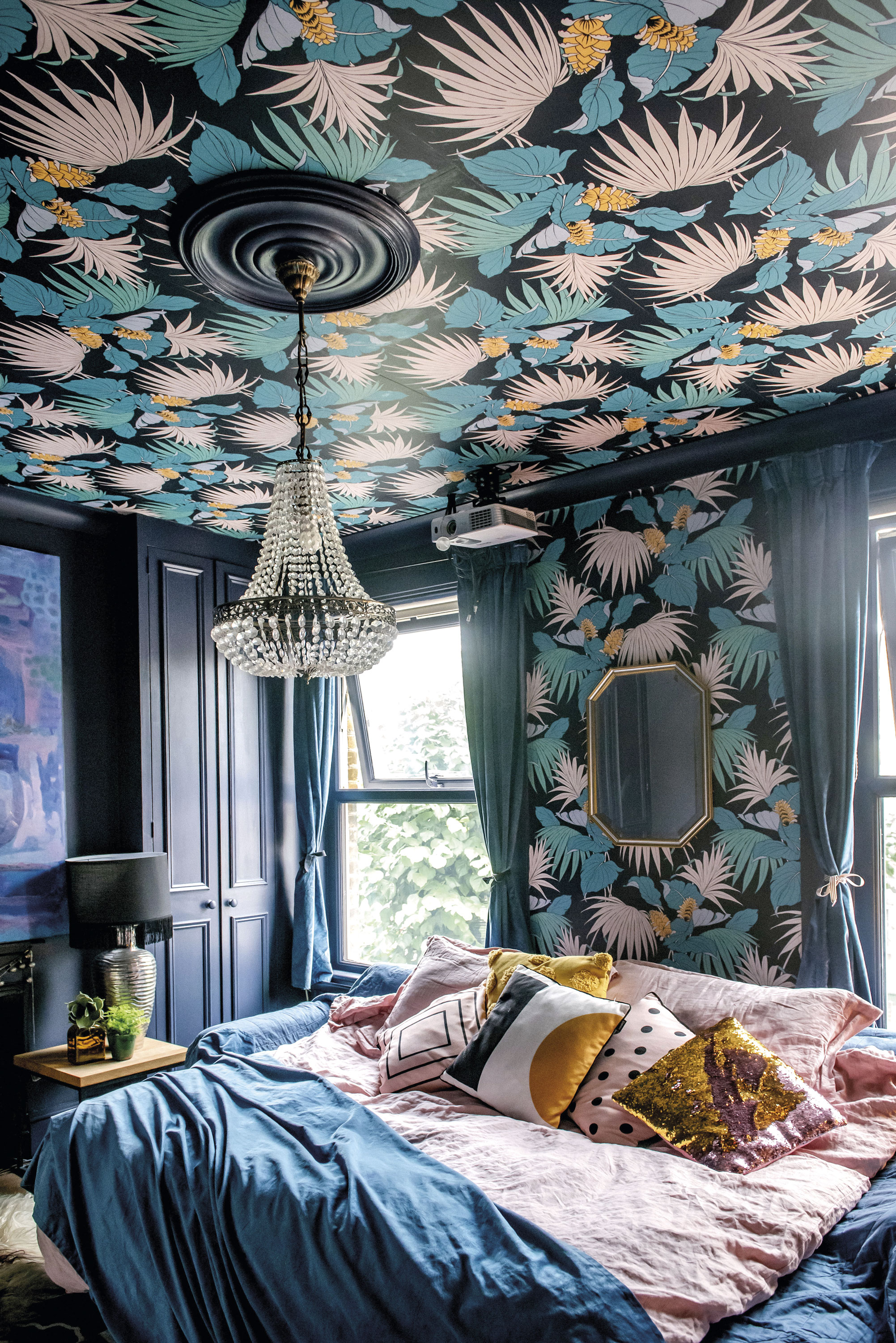 Beth’s bedroom has both a youthful and a grown-up air about it. Deep blue walls and trim perfectly frame the foliage paper, creating fun focal points on both ceiling and walls, while pastel pink and ochre accessories pepper the scheme with playfulness Beth’s bedroom has both a youthful and a grown-up air about it. Deep blue walls and trim perfectly frame the foliage paper, creating fun focal points on both ceiling and walls, while pastel pink and ochre accessories pepper the scheme with playfulness