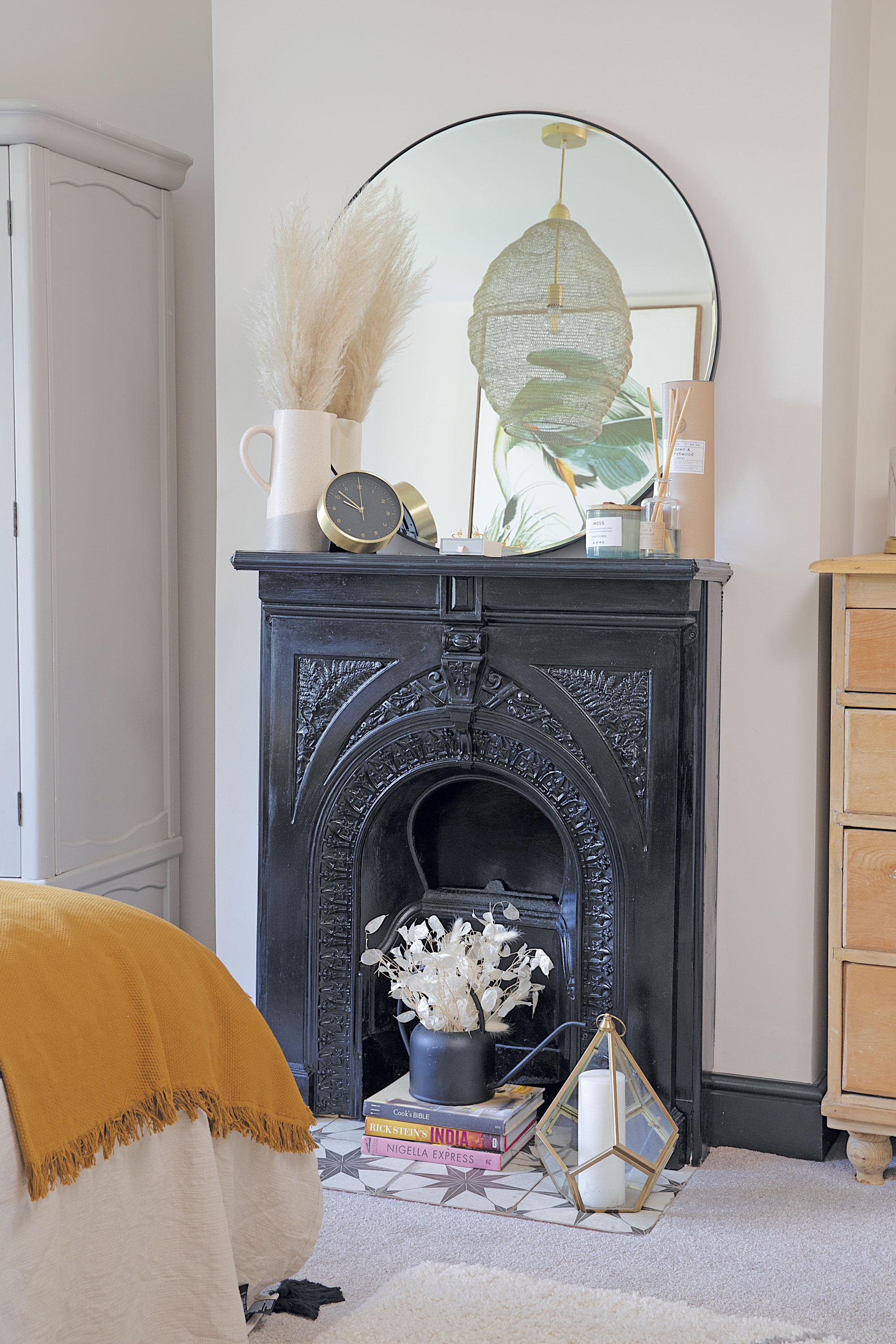 ‘We painted the reclaimed fireplace black for a more dramatic look and propped a mirror from Wayfair above,’ says Laura. ‘The wardrobe came from a furniture auction and I painted it pale grey when we moved here’ ‘We painted the reclaimed fireplace black for a more dramatic look and propped a mirror from Wayfair above,’ says Laura. ‘The wardrobe came from a furniture auction and I painted it pale grey when we moved here’