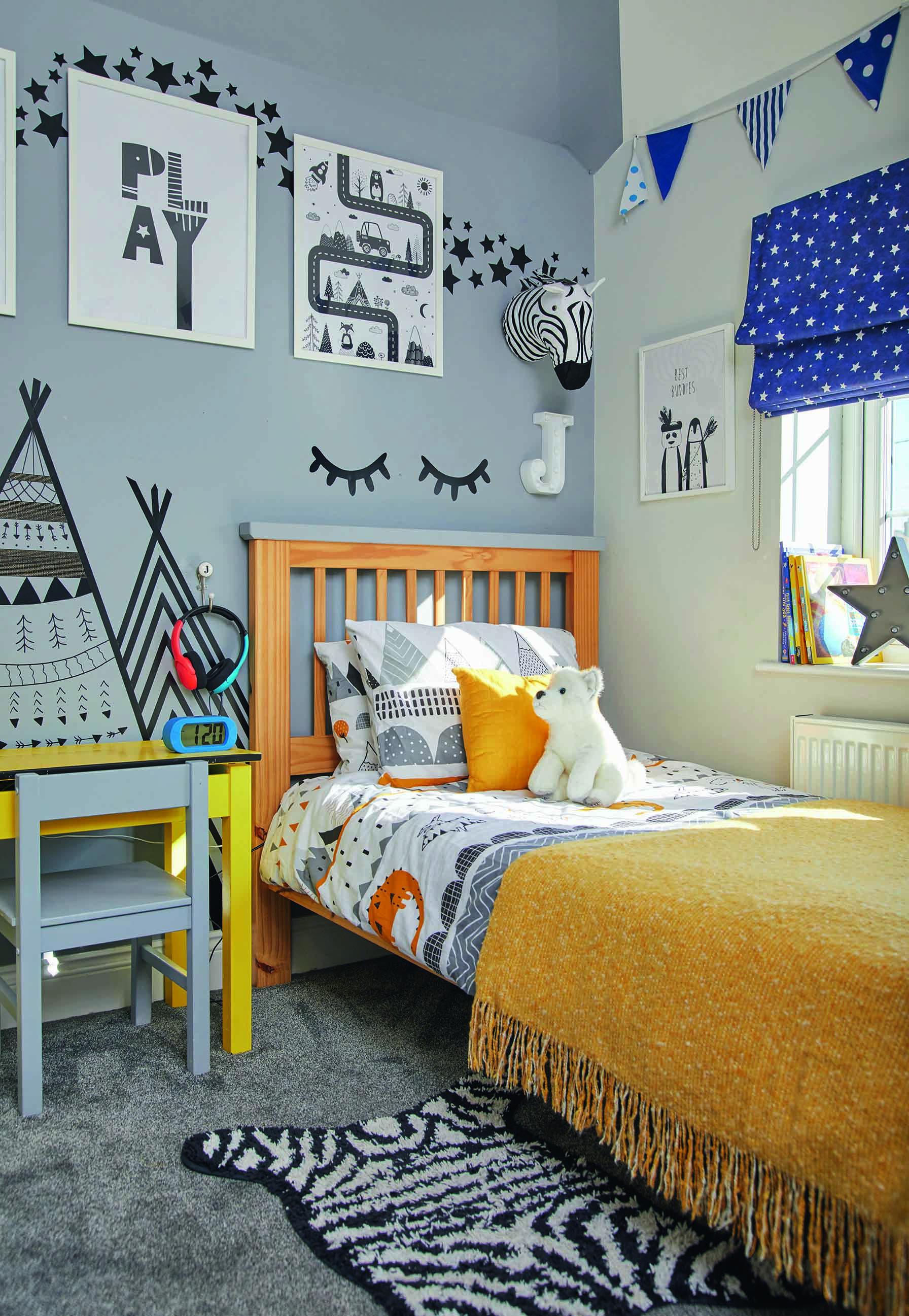 This kid's room has a yellow, blue and grey colour palette with prints on the wall from IKEA