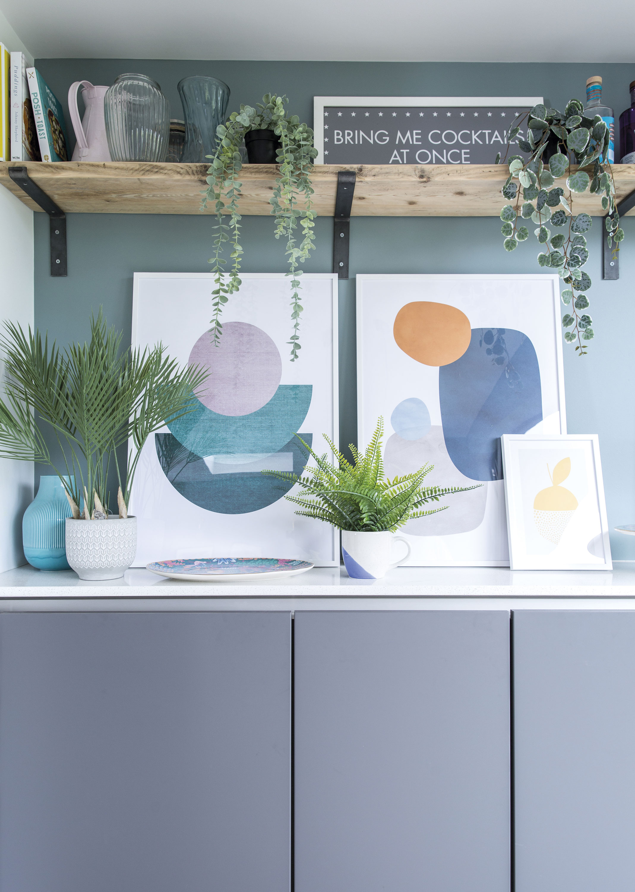 Framed abstract prints decorate the sideboard, which matches the kitchen area and provides more storage for the kids’ toys