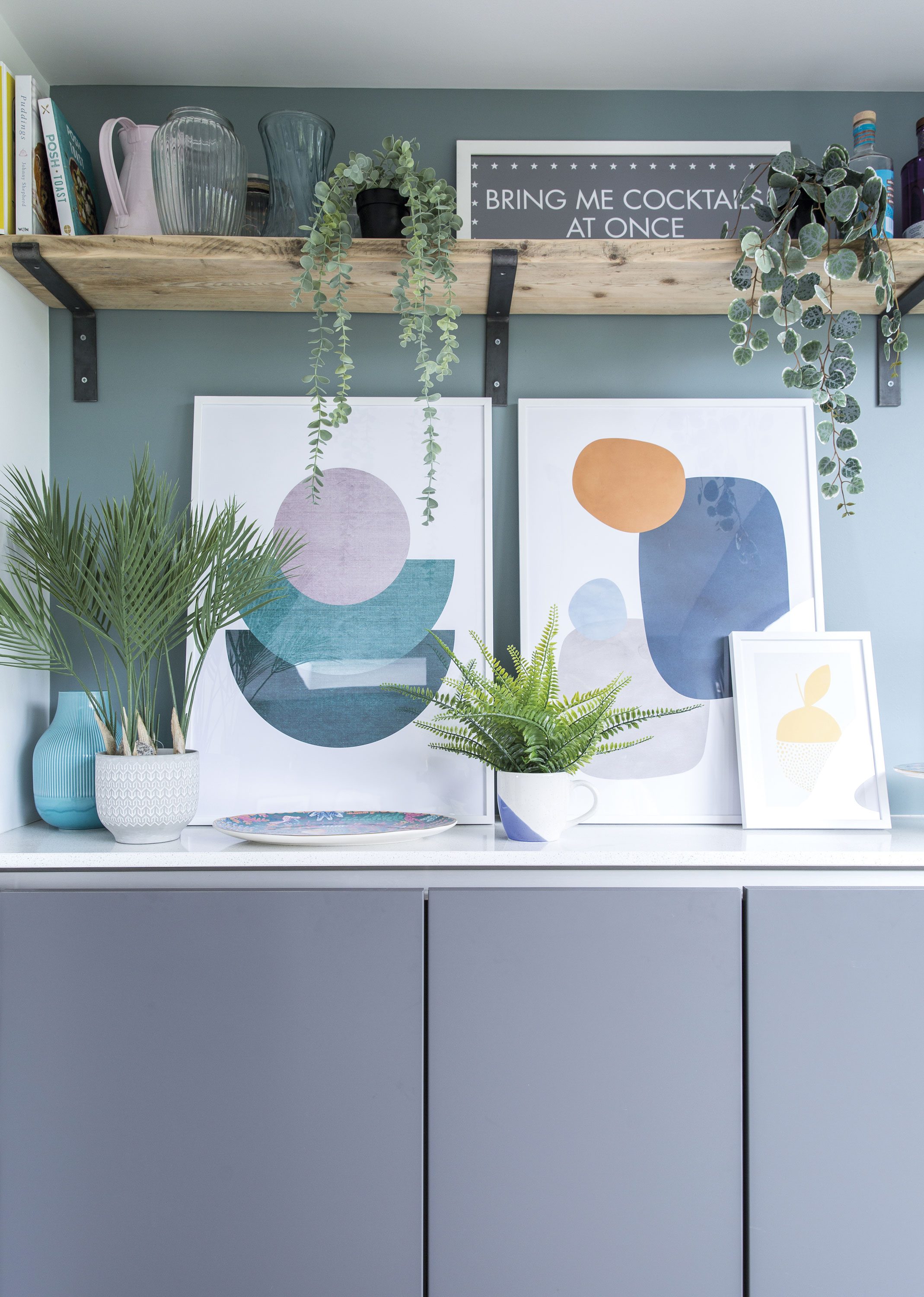 Framed abstract prints decorate the sideboard, which matches the kitchen area and provides more storage for the kids’ toys