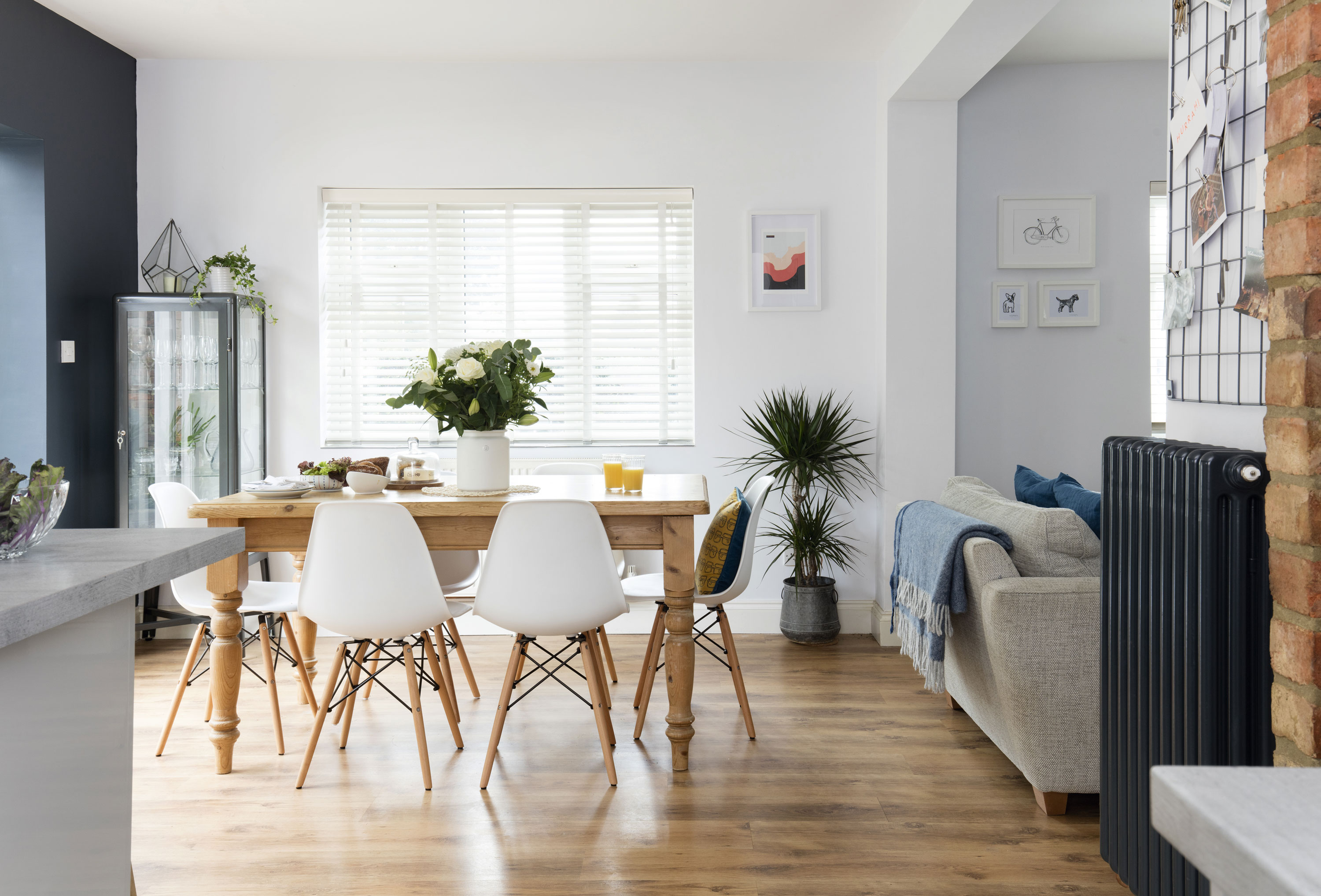 The large farmhouse-look dining table adds a rustic touch to the room, which in turn adds some warmth to the simply styled space. The six matching Eames-style chairs add a designer touch