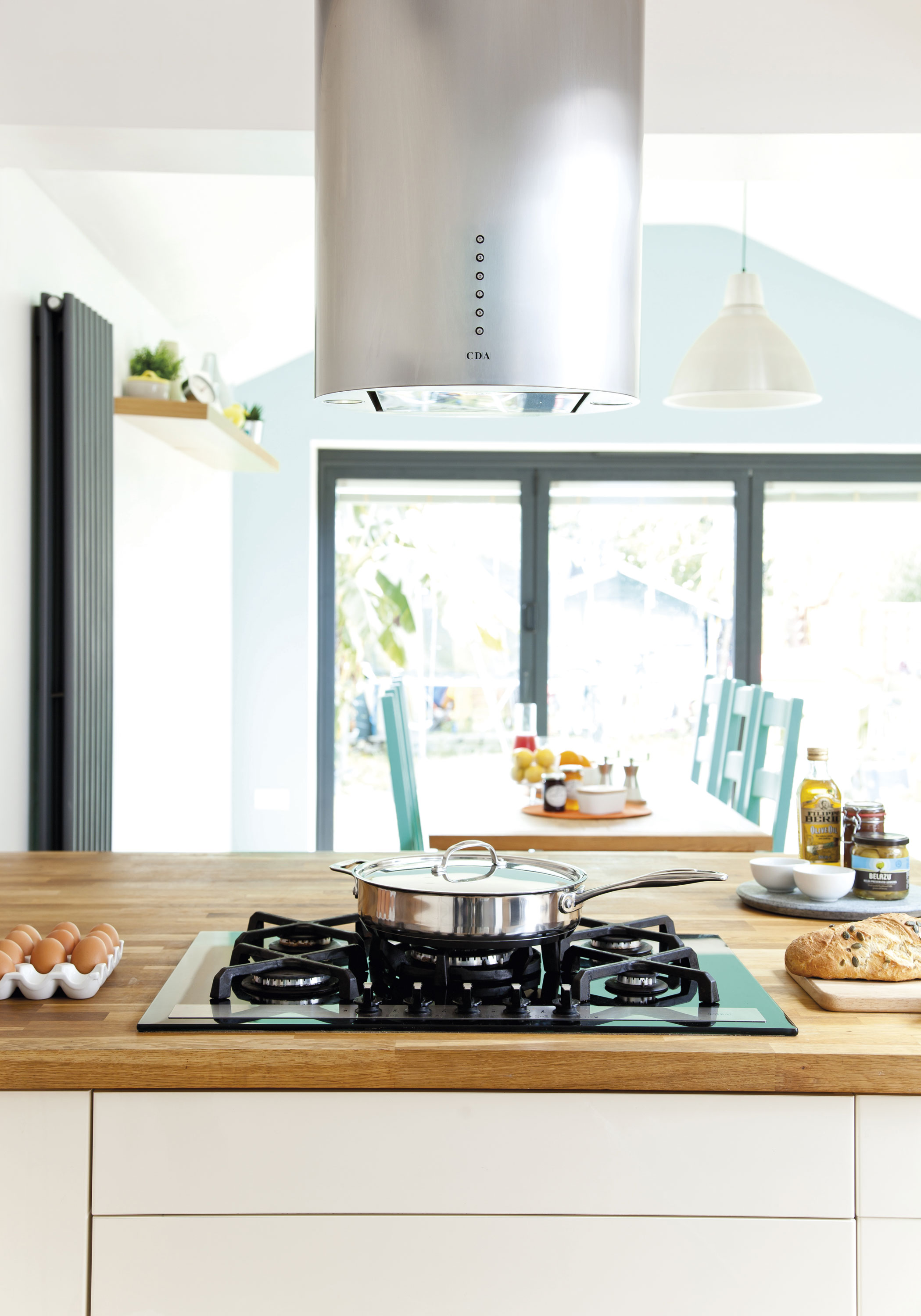 A large room like this needs some statement pieces to give it wow factor. The chimney-style extractor defines the kitchen area while the oversized pendant lamp frames the dining area