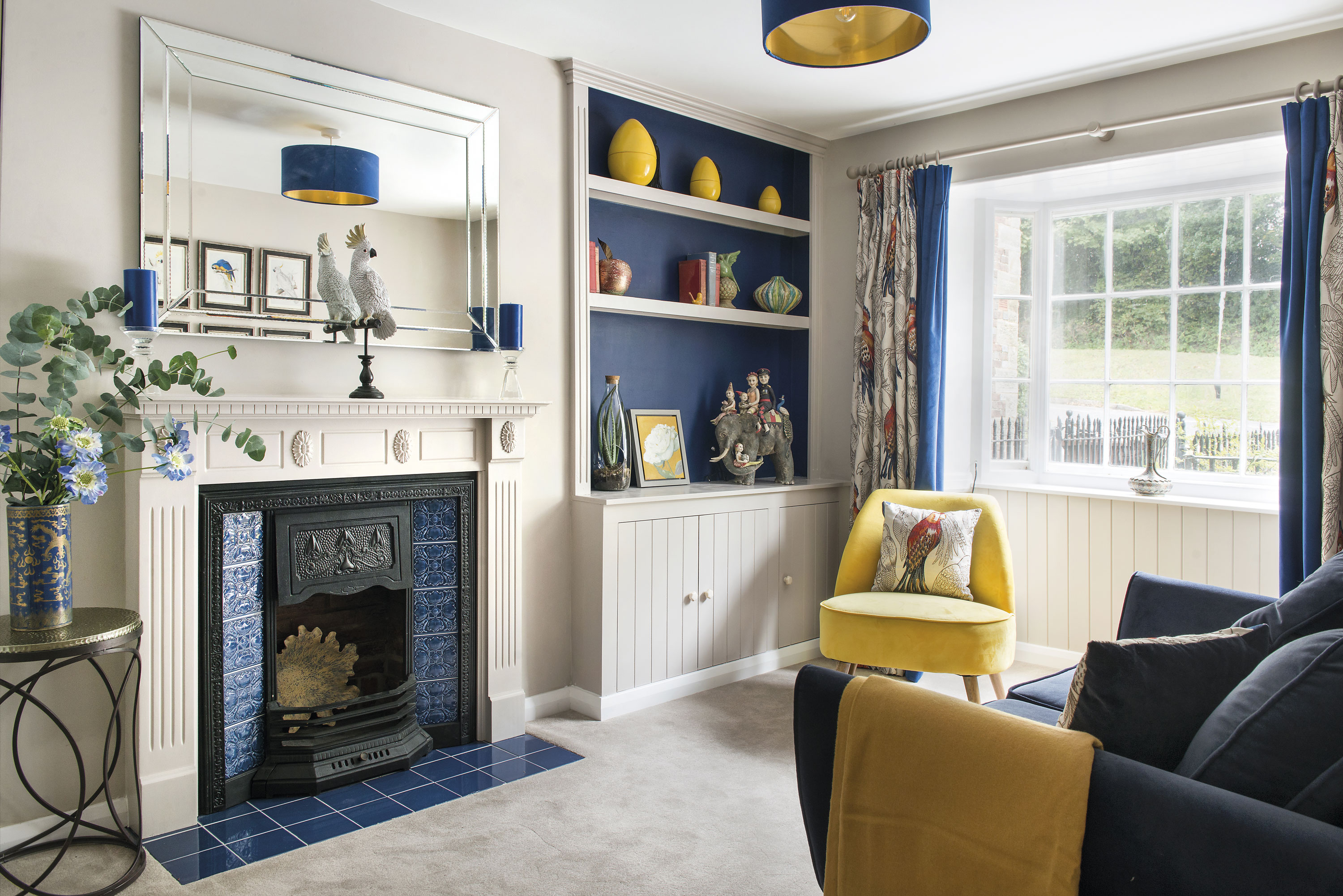 The front room has been turned into a snug with strong blue tones and a bird theme. The fireplace was bought on Facebook Marketplace and upcycled with Minton Hollis Scuba Blue tiles from Topps. ‘The blue velvet and gold lampshade was specially made by Millie & Rose Designs,’ says Charlie The front room has been turned into a snug with strong blue tones and a bird theme. The fireplace was bought on Facebook Marketplace and upcycled with Minton Hollis Scuba Blue tiles from Topps. ‘The blue velvet and gold lampshade was specially made by Millie & Rose Designs,’ says Charlie